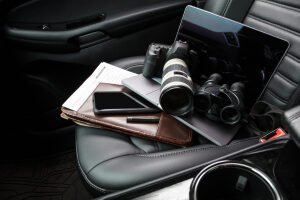 Private investigator tools on car seat Tools for private investigation including camera, smartphone, laptop and binoculars